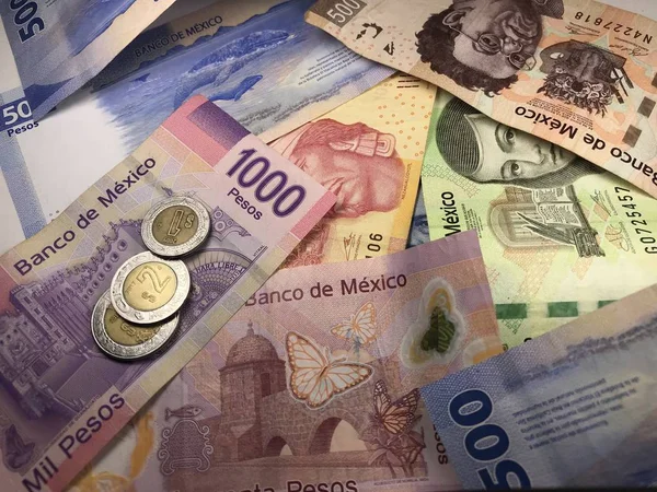 Veel gemengde Mexicaanse peso-biljetten verspreid over een houten bureau — Stockfoto