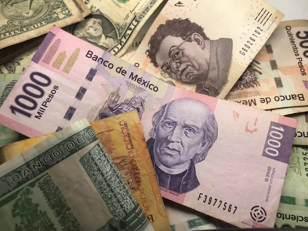Muitas contas de peso mexicanas mistas espalhadas por uma mesa de madeira — Fotografia de Stock