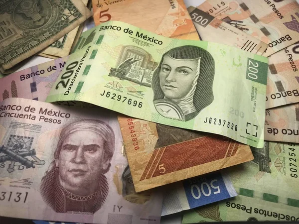 Muchos billetes mixtos de peso mexicano repartidos sobre un escritorio de madera — Foto de Stock