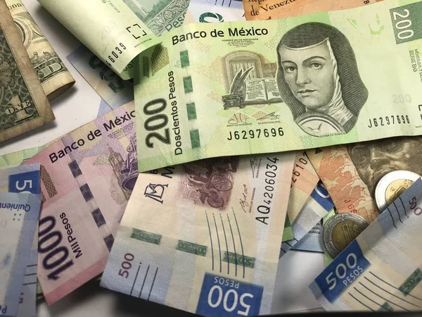 Mnoho smíšených mexických Peso se rozprostřel na dřevěném stole — Stock fotografie