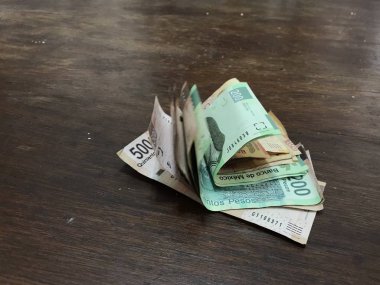 Birçok karışık Meksika pezosu faturaları ahşap bir masa üzerine yayılmış