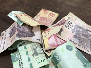 Birçok karışık Meksika pezosu faturaları ahşap bir masa üzerine yayılmış