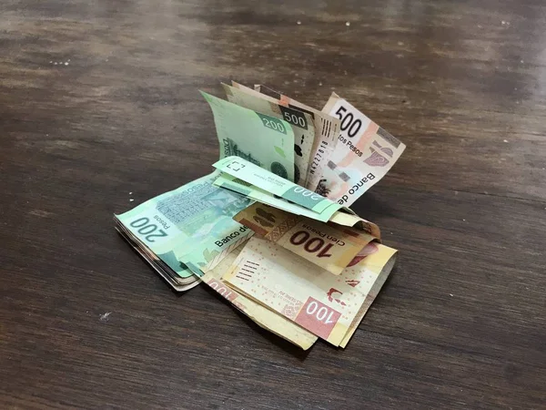 许多混合墨西哥比索钞票分布在一张木桌上 — 图库照片
