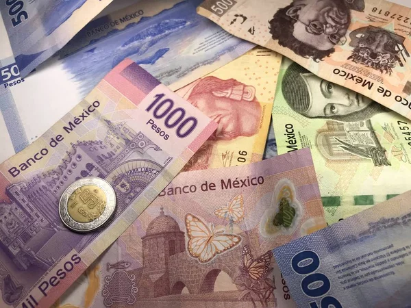 Muchos billetes mixtos de peso mexicano repartidos sobre un escritorio de madera — Foto de Stock