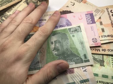 Meksika pezosu faturaları üzerlerinde bir el ile düz bir yüzeye rasgele yayıldı