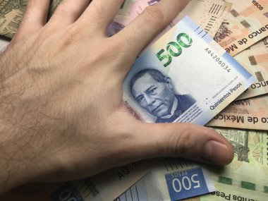 Meksika pezosu faturaları üzerlerinde bir el ile düz bir yüzeye rasgele yayıldı