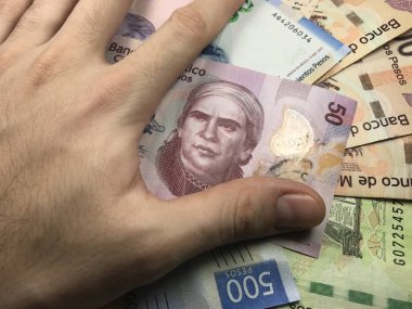 Meksika pezosu faturaları üzerlerinde bir el ile düz bir yüzeye rasgele yayıldı