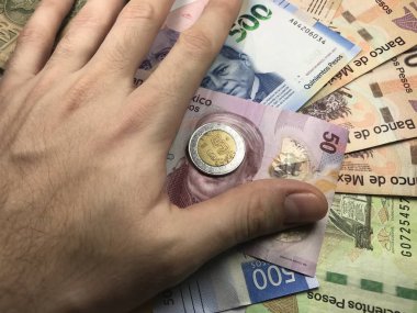 Meksika pezosu faturaları üzerlerinde bir el ile düz bir yüzeye rasgele yayıldı