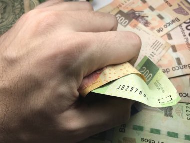 Meksika pezosu faturaları üzerlerinde bir el ile düz bir yüzeye rasgele yayıldı