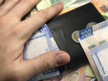 Meksika pezosu faturaları üzerlerinde bir el ile düz bir yüzeye rasgele yayıldı