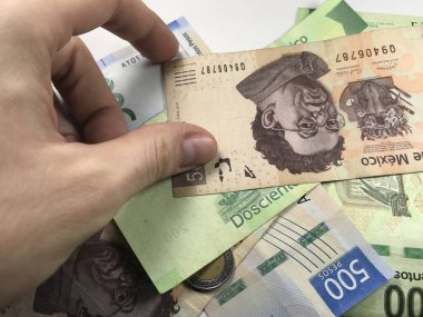 Meksika pezosu faturaları üzerlerinde bir el ile düz bir yüzeye rasgele yayıldı