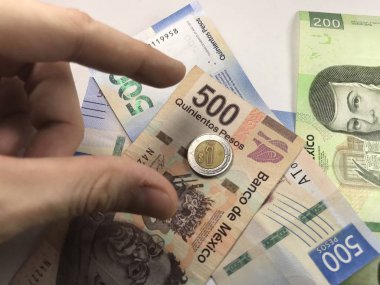 Meksika pezosu faturaları üzerlerinde bir el ile düz bir yüzeye rasgele yayıldı