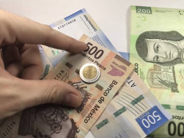 Meksika pezosu faturaları üzerlerinde bir el ile düz bir yüzeye rasgele yayıldı