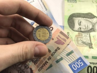 Meksika pezosu faturaları üzerlerinde bir el ile düz bir yüzeye rasgele yayıldı