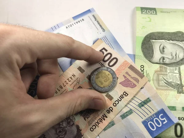 Peso mexicano contas espalhadas aleatoriamente sobre uma superfície plana com uma mão sobre eles — Fotografia de Stock