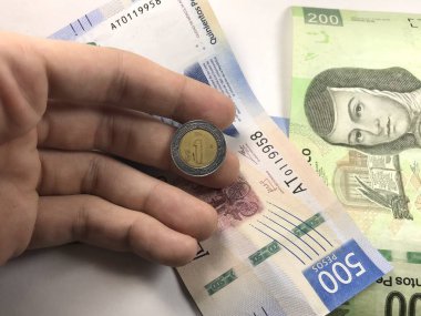 Meksika pezosu faturaları üzerlerinde bir el ile düz bir yüzeye rasgele yayıldı