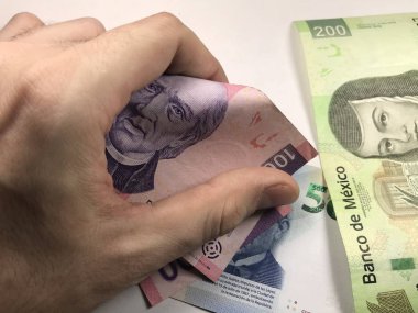 Meksika pezosu faturaları üzerlerinde bir el ile düz bir yüzeye rasgele yayıldı