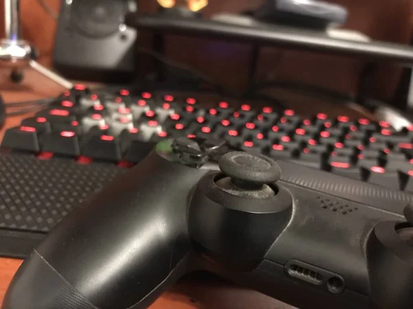 Modern black gaming controller over a wooden desk with a mechanical keyboard and desktop computer — Stock Photo, Image