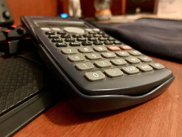 Calculadora científica sobre un teclado de ordenador en un escritorio de madera —  Fotos de Stock