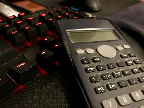 Calculatrice scientifique sur un clavier d'ordinateur sur un bureau en bois — Photo