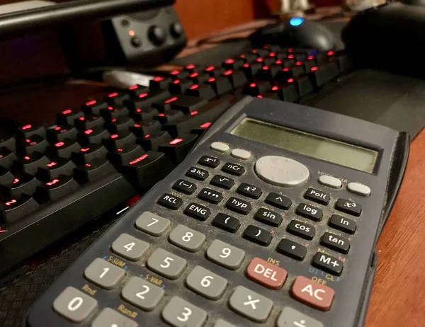 Calcolatrice scientifica su una tastiera di computer su una scrivania di legno — Foto Stock
