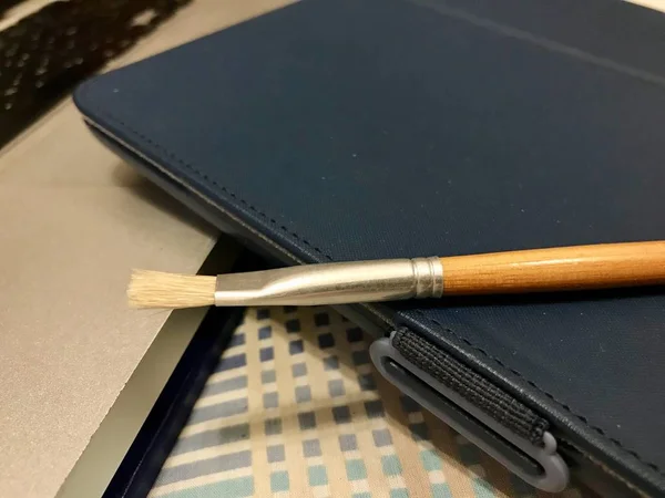 Verfborstel over een Tablet in een blauwe bekleding van de stof en een zilver metallic laptop computer — Stockfoto