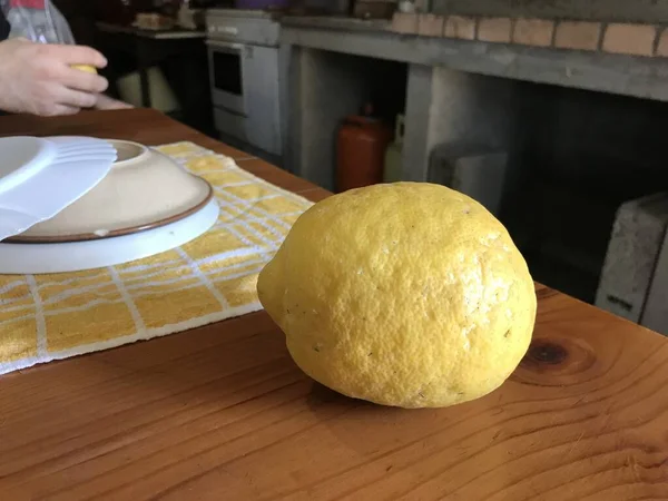 Arkaplanda tabaklar olan ahşap bir masanın üstünde limon. — Stok fotoğraf