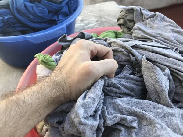 Korb voller sauberer Wäsche mit einer Hand, die ein paar Kleider pflückt — Stockfoto