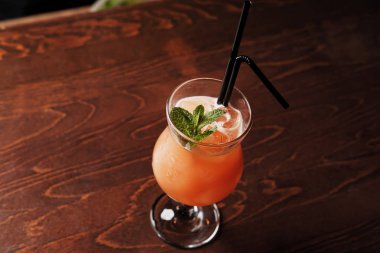 Temelinde cin, vişne, portakal ve likör Benediktin, nar suyu, ananas ve limon suyu acı sanat ilavesi ile alkollü kokteyl.