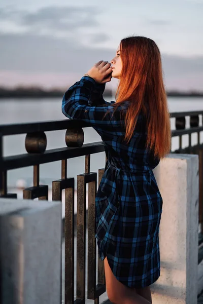 Спокойная девушка, стоящая одна на набережной перед забором набережной . — стоковое фото