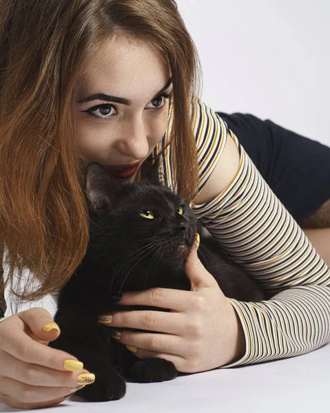 Mädchen mit schwarzer verschmitzter Katze auf weißem Hintergrund. fast isoliert Stockbild