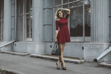 Çiçekli Kırmızı kısa elbiseli güzel tabaklanmış şık esmer kız pozlar duran ve üzerinde sokak şehir yürüyüş flört