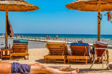 Tatil plaj ve tatilcilerin güneşin kızıl deniz güneş yanığı kıyısında şezlong içinde görünüm