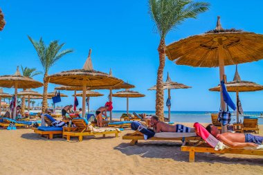 Tatil plaj ve tatilcilerin güneşin kızıl deniz güneş yanığı kıyısında şezlong içinde görünüm