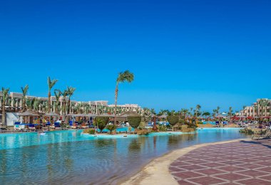 Plaj ve deniz kıyısında güneşli bir gün mavi gökyüzünün altında palmiye ağaçları oteller rekreasyon çevrenin görünümü