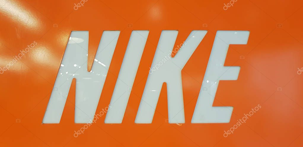 KUALA LUMPUR, MALAYSIA - AUGUST 25, 2018: Nike Logo on orange background. Nike is an American corporation that was founded on January 25, 1964.