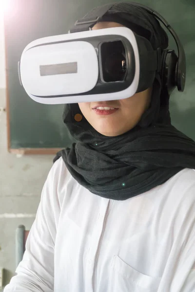 Malay Girl smiling at the classroom wearing VR headset