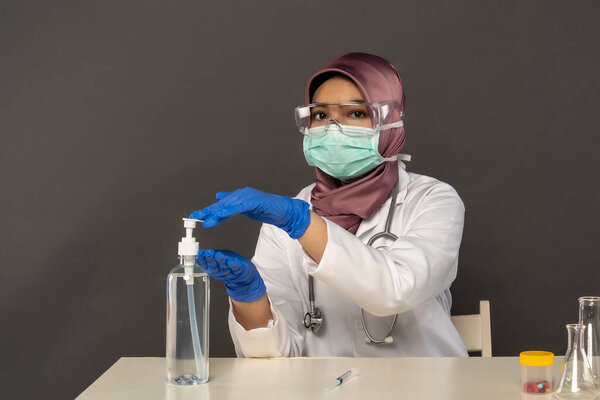 Science lab concept, Cute Malay Woman wearing hijab using sanitizer
