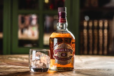 Chivas Regal viski şişe ve cam buz küpleri koyu bar ahşap tablo ile. Chivas Regal ünlü popüler yaşlı Scotch viski markasıdır.