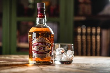 Chivas Regal viski şişe ve cam buz küpleri koyu bar ahşap tablo ile. Chivas Regal ünlü popüler yaşlı Scotch viski markasıdır.