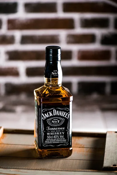 Jack Daniels whiskey bottle on an wooden box. Brick wall on background. Jack Daniels is the best-selling American whiskey in the world and a famous whiskey brand