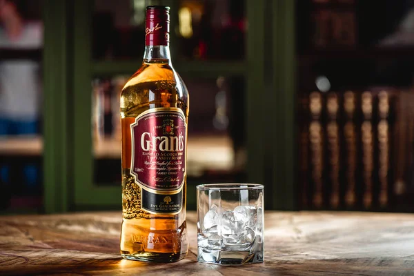 Grant'ın viski şişe ve cam buz küpleri koyu bar ahşap tablo ile. Hibe olduğunu harmanlanmıştır Scotch viski ve bir en dinamik olarak dünya markaları geliştirme