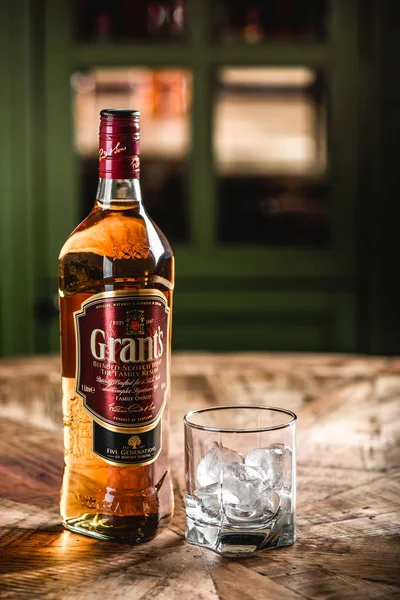 Grant'ın viski şişe ve cam buz küpleri koyu bar ahşap tablo ile. Hibe olduğunu harmanlanmıştır Scotch viski ve bir en dinamik olarak dünya markaları geliştirme