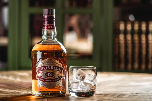 Chivas Regal viski şişe ve cam buz küpleri koyu bar ahşap tablo ile. Chivas Regal ünlü popüler yaşlı Scotch viski markasıdır.