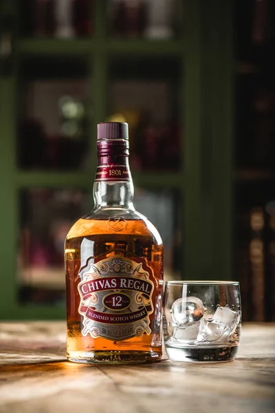 Chivas Regal viski şişe ve cam buz küpleri koyu bar ahşap tablo ile. Chivas Regal ünlü popüler yaşlı Scotch viski markasıdır.