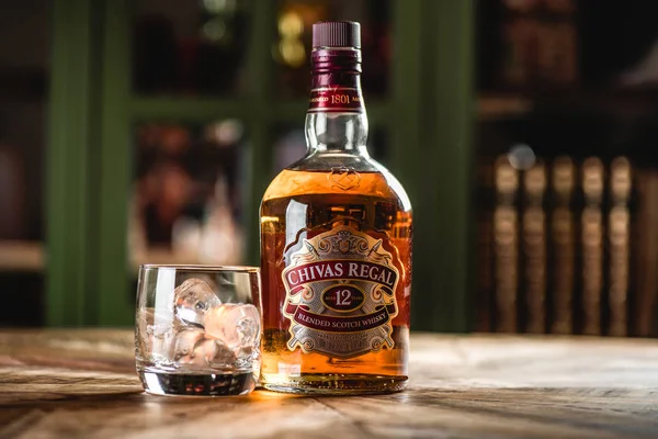 Chivas Regal viski şişe ve cam buz küpleri koyu bar ahşap tablo ile. Chivas Regal ünlü popüler yaşlı Scotch viski markasıdır.