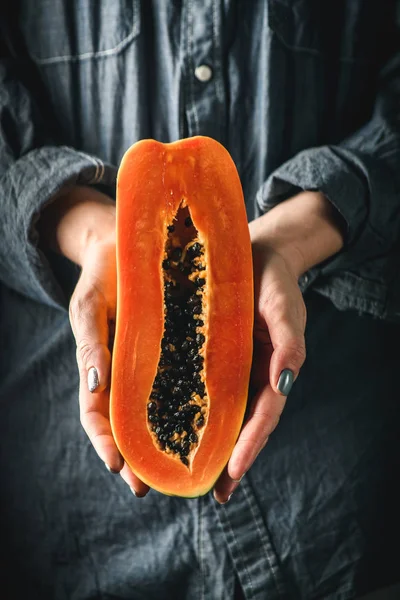 Papaya Asya egzotik meyve. Yarı tropik meyve kadınların elinde. Turuncu hamuru siyah tohumları