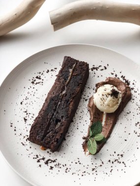 Beyaz plaka üzerinde ahşap dallar yanında çikolata tatlı kek