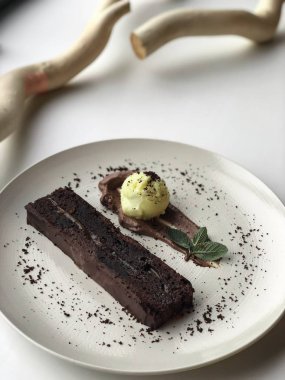 Beyaz plaka üzerinde ahşap dallar yanında çikolata tatlı kek