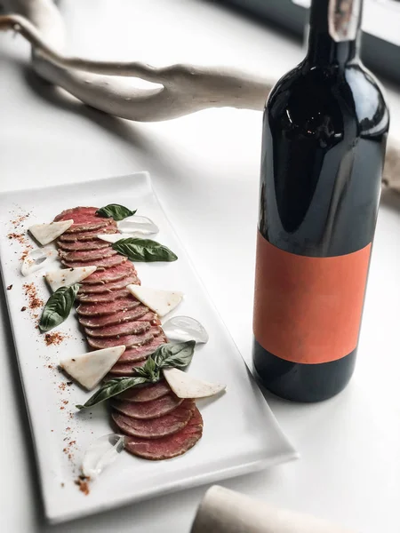 Peynir ve bir şişe kırmızı şarap ile bir tabak prosciutto